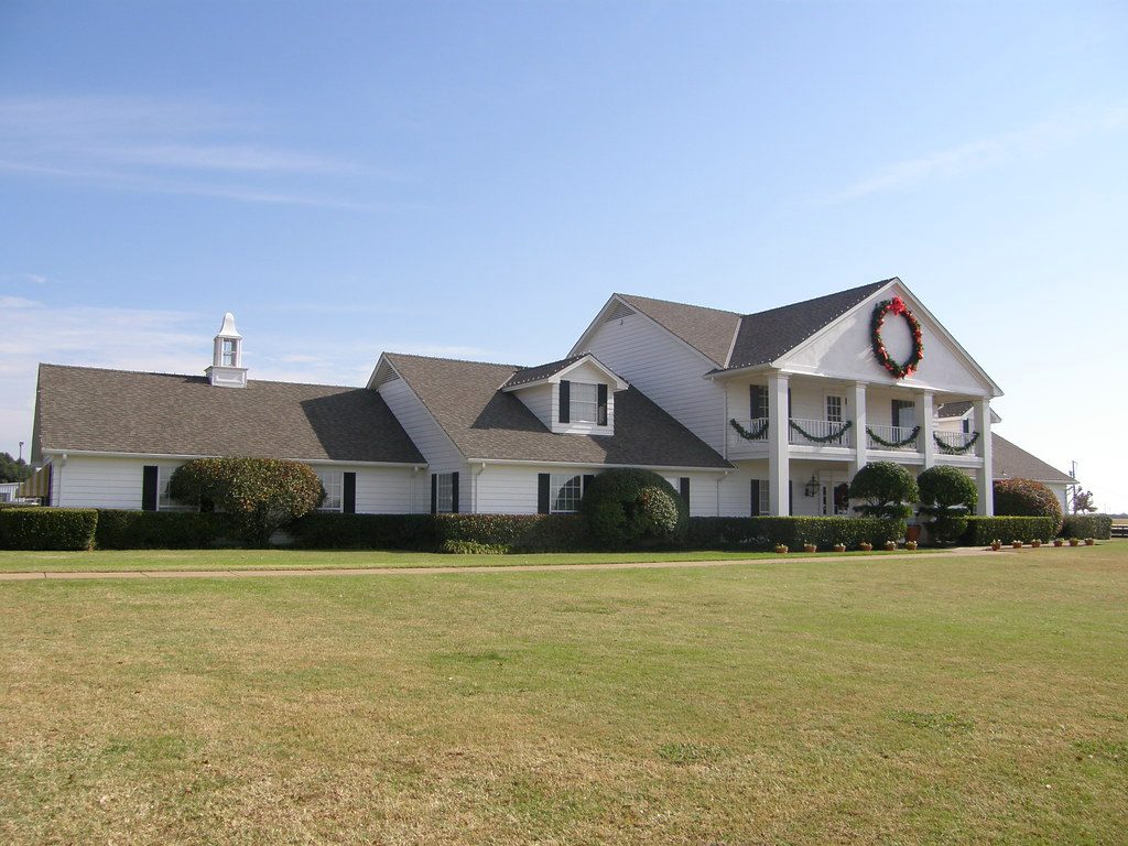 White Texas ranch house behind a broad lawn